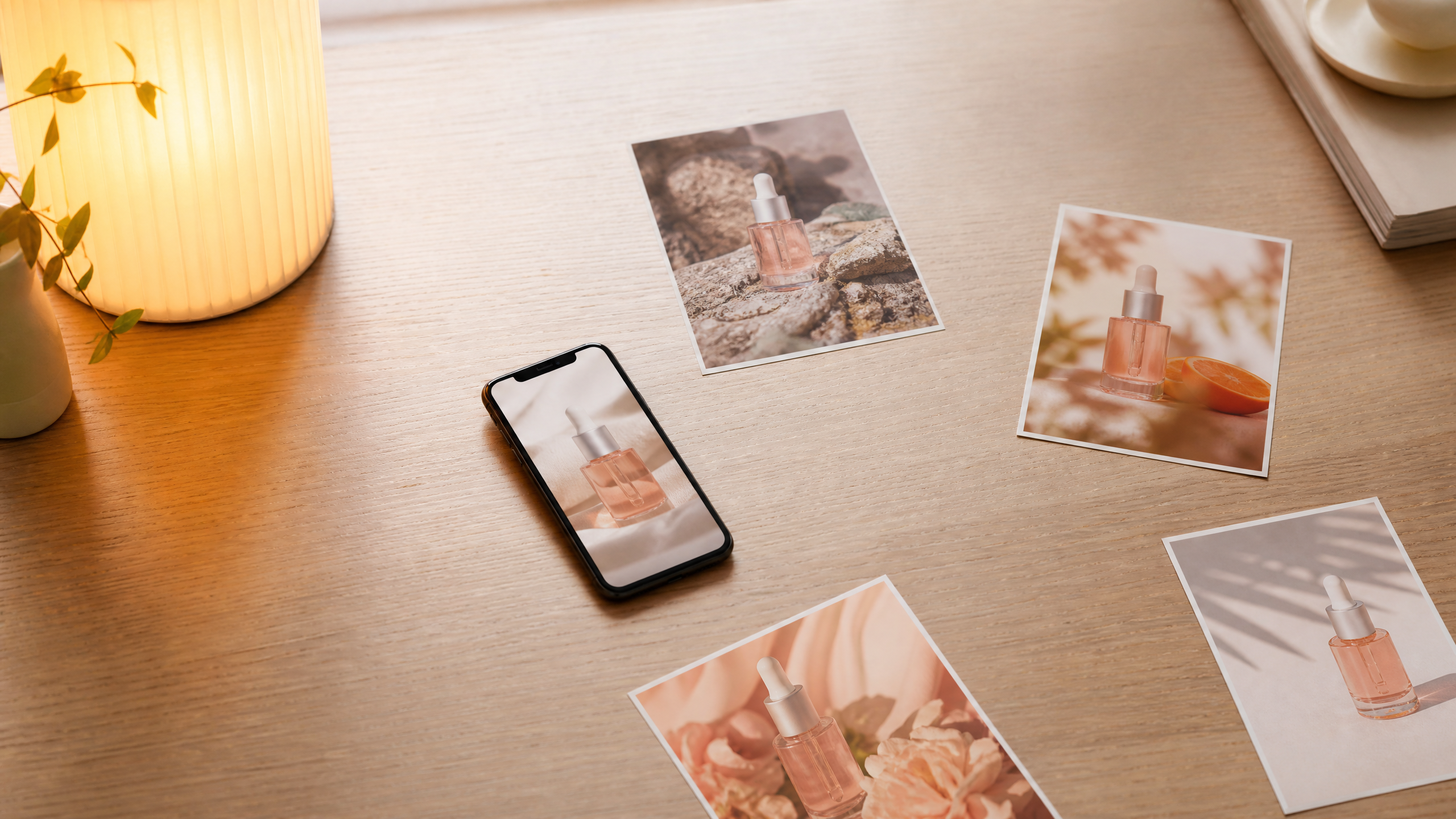 Un téléphone posé sur un bureau affiche une photo de produit cosmétique, entouré de tirages papier du même produit dans différents décors.